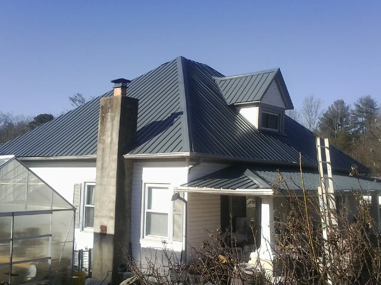 Dark blue standing seam metal roof on a white farmhouse with dormer — Slate & Tile Roof Repair by Roofing Brothers in Elizabeth