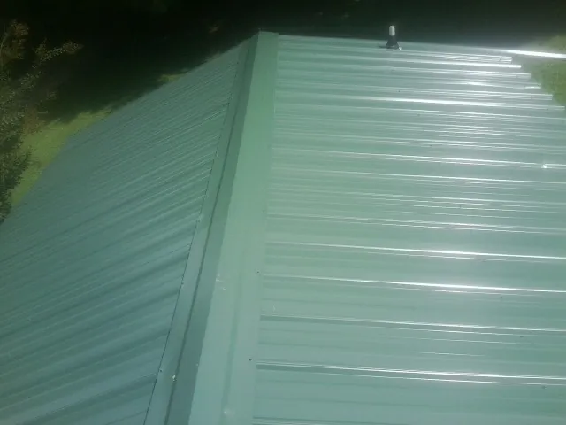 New green metal panels meeting at the ridge of a roof — Flat Roof Repair work by our crew in Elizabeth